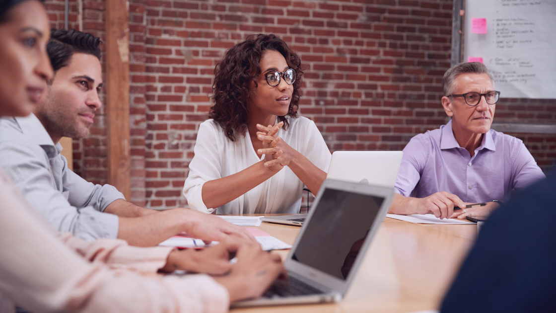 Diverse group of professionals of varying ages in a meeting, symbolizing age inclusion in the workplace — banner for blog post titled 'Should Age Matter When Hiring? Understanding the ETI Advantage.